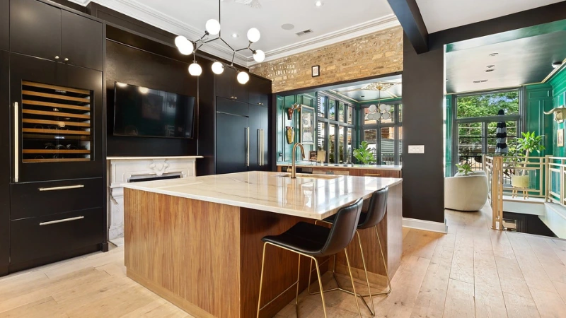 Modern kitchen in Chicago with a wood-paneled island, marble countertop, black cabinetry, and a sputnik chandelier overhead.