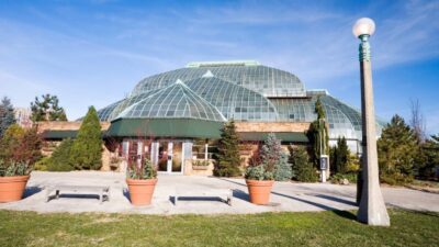 The Lincoln Park Conservatory building sits under a clear blue sky in Chicago.