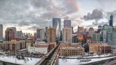 Panoramic winter view of the Chicago skyline with snow-covered rooftops and an elevated train running through the West Loop neighborhood.