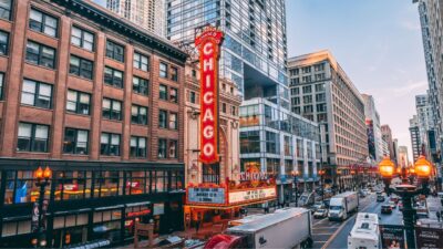 Chicago Theatre marquee glowing above a busy downtown street at dusk.