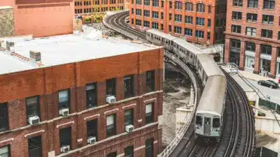 Chicago L train rounding an elevated curve through a red-brick urban neighborhood.
