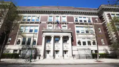Historic brick school building with tall columns, an American flag above the entrance, and a bicycle parked outside in North Center, Chicago.
