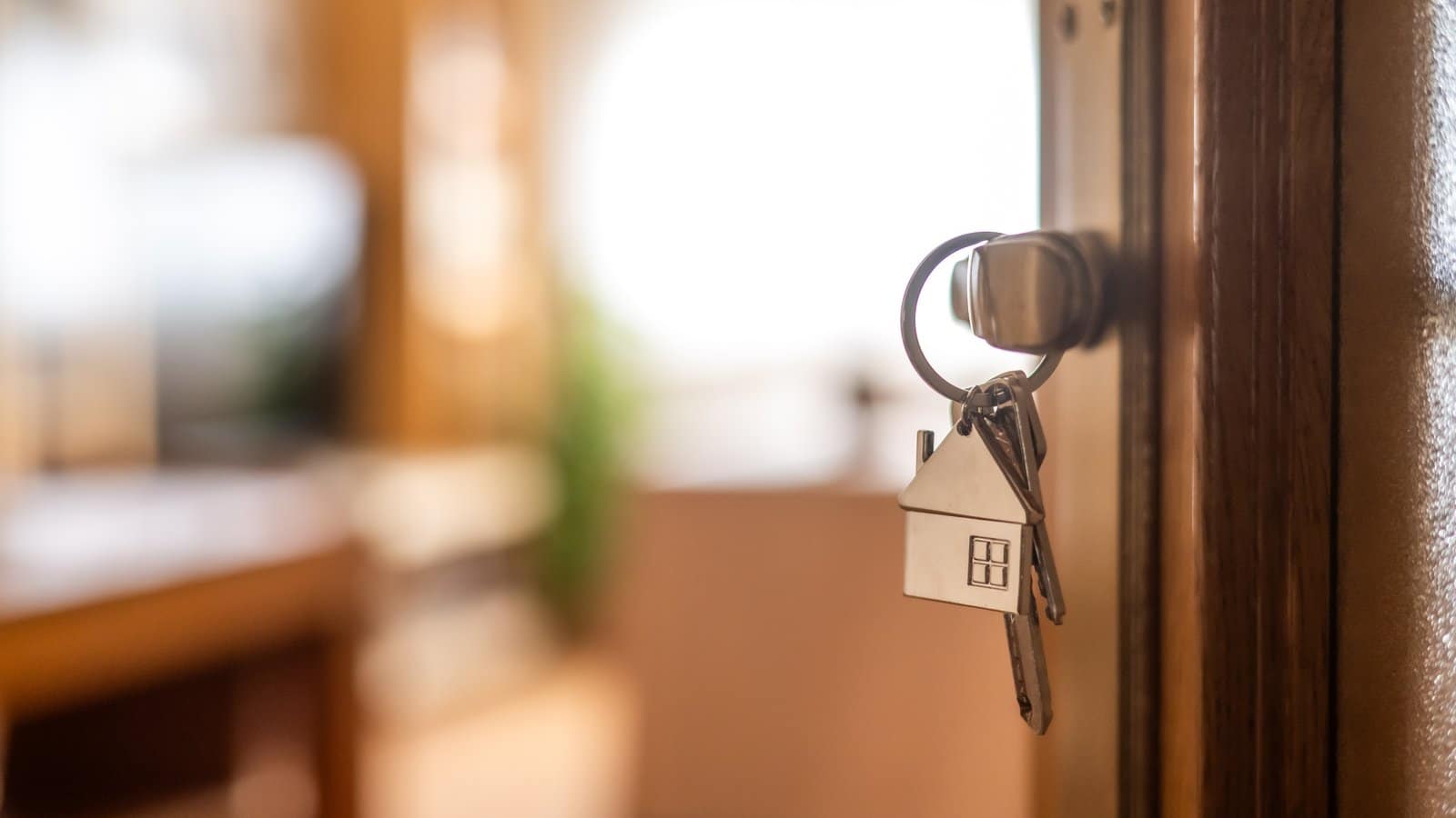 House key with a house-shaped keychain hanging in a front door lock on closing day