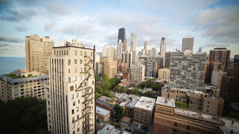 High view over Gold Coast high-rises and vintage buildings toward the Chicago skyline and Lake Michigan