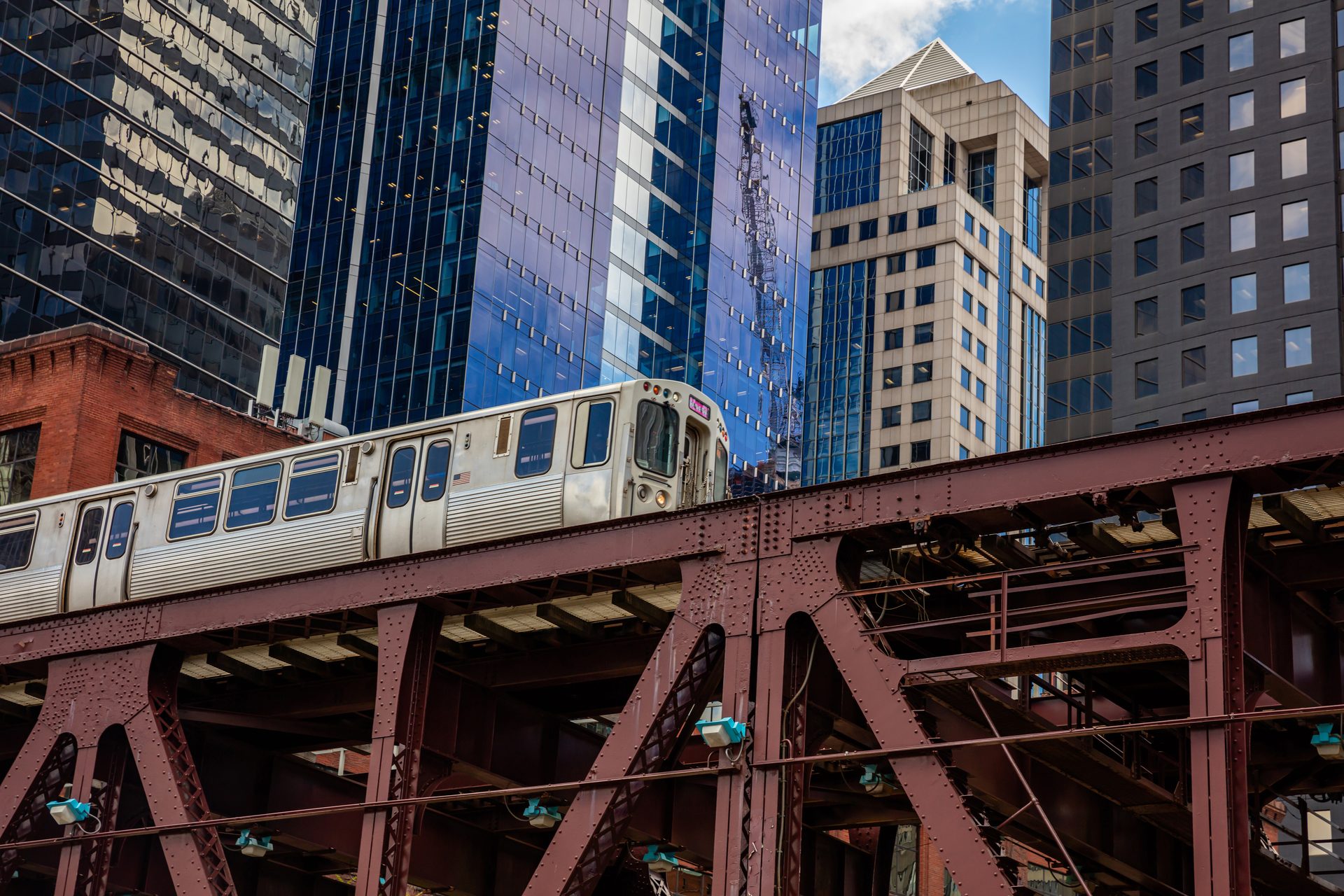 A CTA 'L' train crossing an elevated bridge with downtown Chicago skyscrapers behind it.