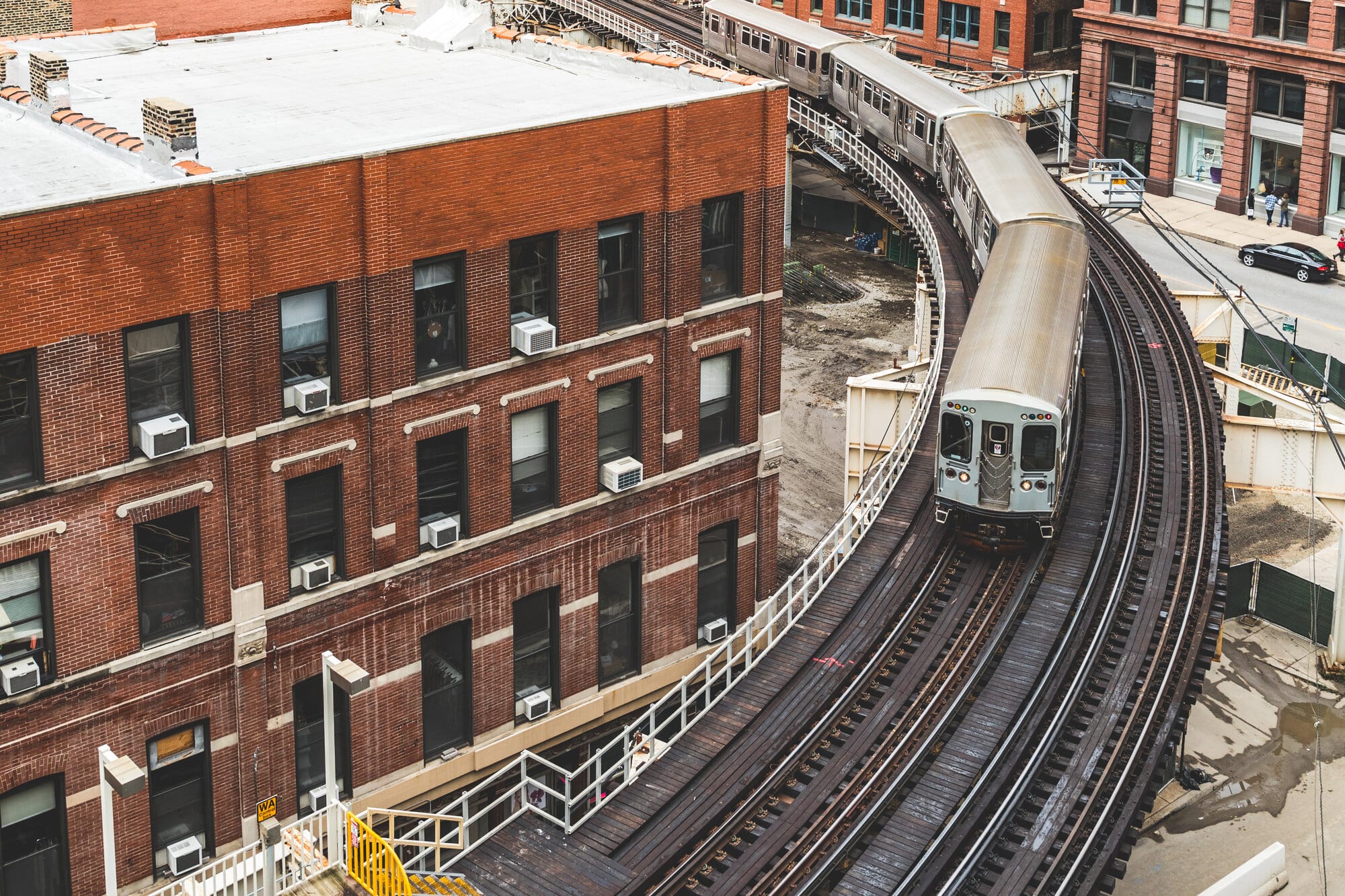 Elevated L train rounding a curve past brick buildings in Chicago